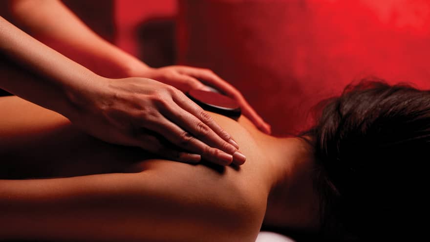 Hands rub woman's bare shoulders during Fusion Massage in spa