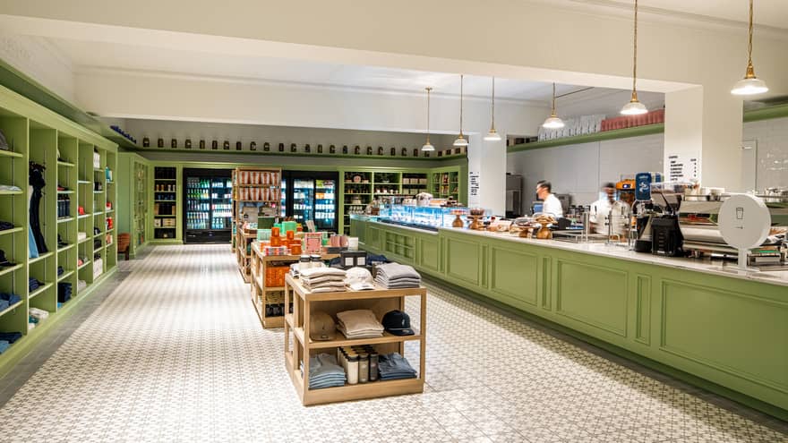 Coffee shop and boutique with white tiled floors and green counters and shelves