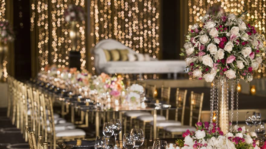 Wine glasses, roses on wedding banquet table before elegant chaise lounge chair 