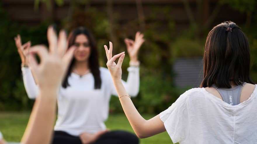Guests doing yoga outdoors on yoga mats with trees in the background