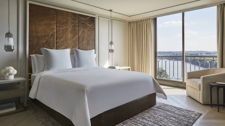 Governor's Suite hotel room bed under large leather headboard with branch pattern, large windows