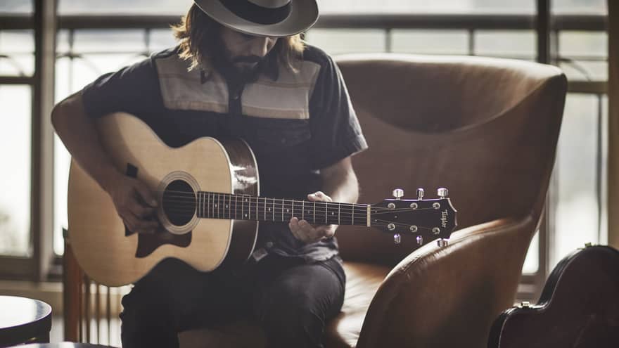 Guitar Concierge plays Taylor acoustic guitar on modern armchair