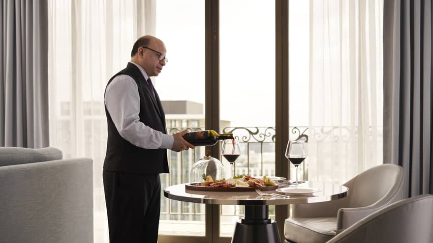 A team member pouring wine in a hotel room.