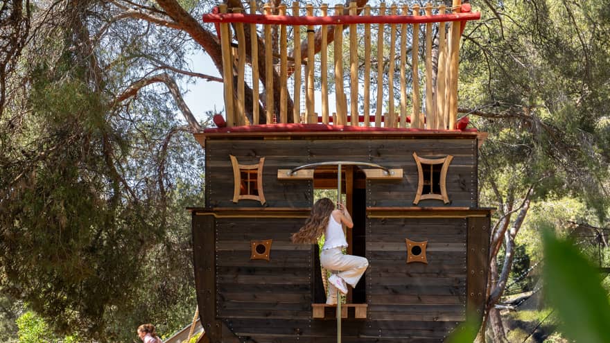 Child climbing a rope on an outdoors pirate ship play set