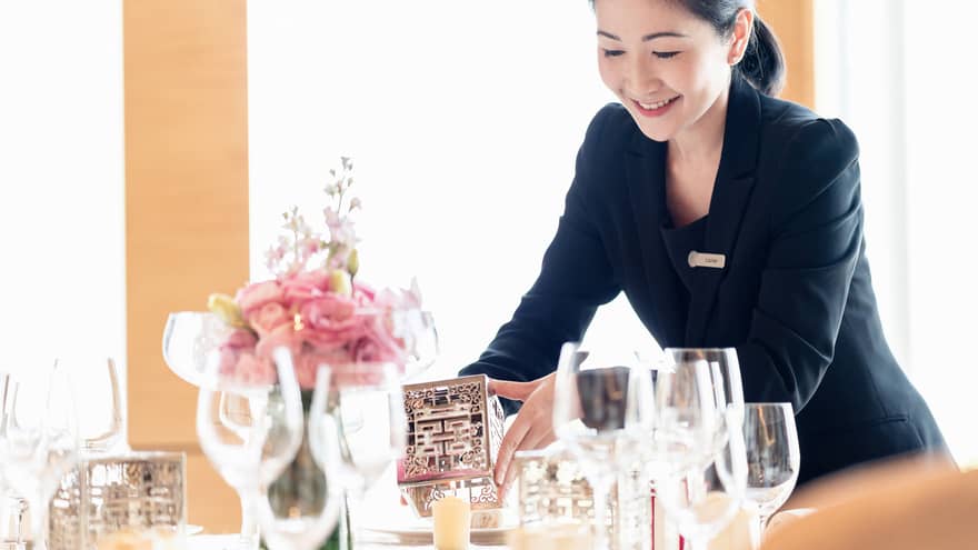 Hotel staff sets candle holder on dining table
