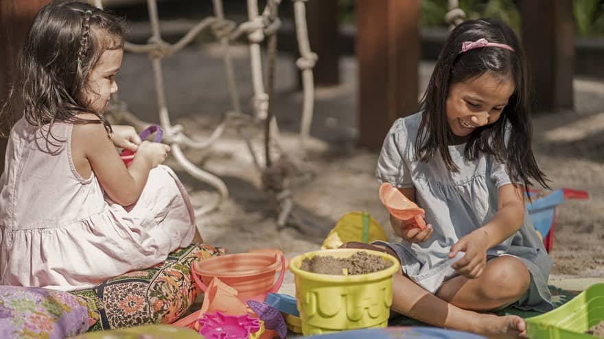 Two young girls play in the sand at Lutong Kids Club