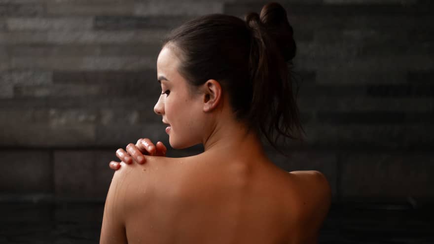 Woman with bare back to camera relaxes in a spa bath