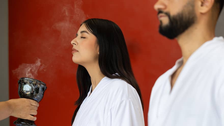 Two people in white spa robes experience  a spa ritual.