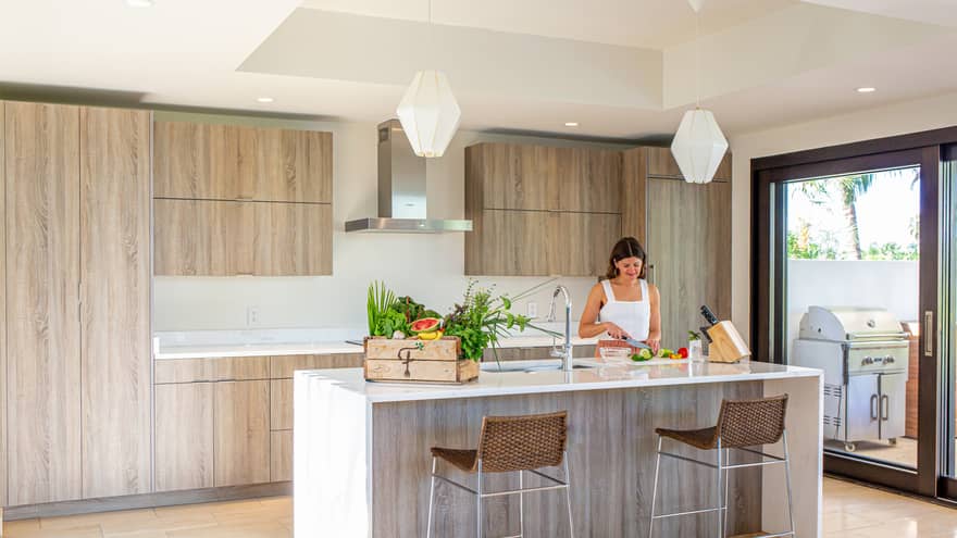 Interior of villa kitchen with woman chopping vegetables