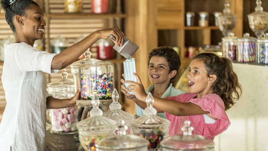 One person standing behind the candy counter, pouring candy into children's candy bags.
