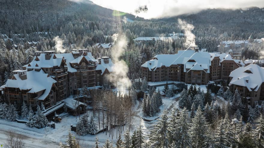 Exterior of property in winter with snow-topped roof and mountains in background