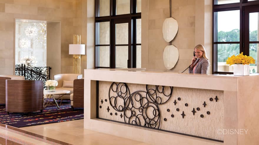 Hotel staff holds telephone behind large marble reception desk in lobby