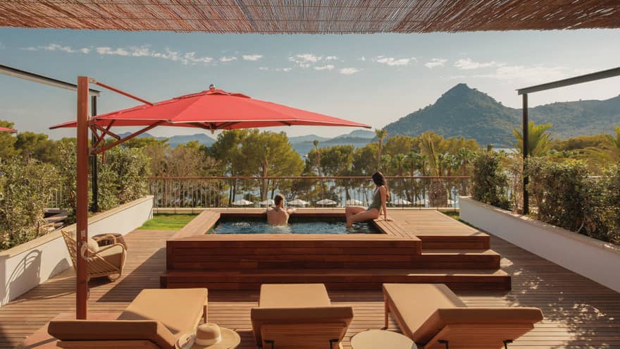 A man and woman relax in a private plunge pool overlooking sea