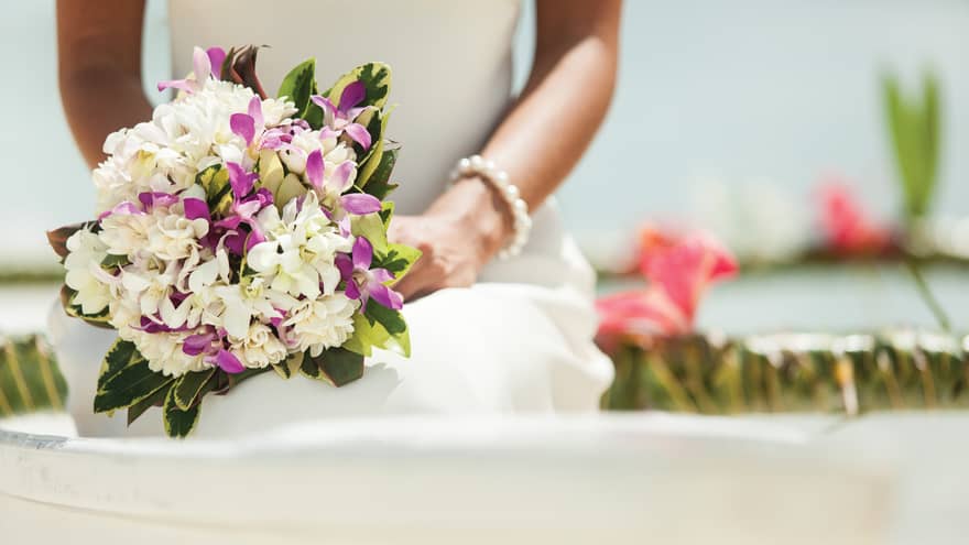 Close-up of bride holding white and purple bouquet of flowers