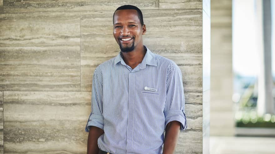Portrait image of smiling personal assistant standing against marble wall