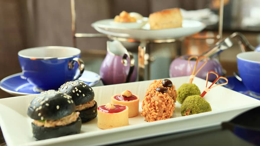 Small appetizers, sweets on white tray near tea service 