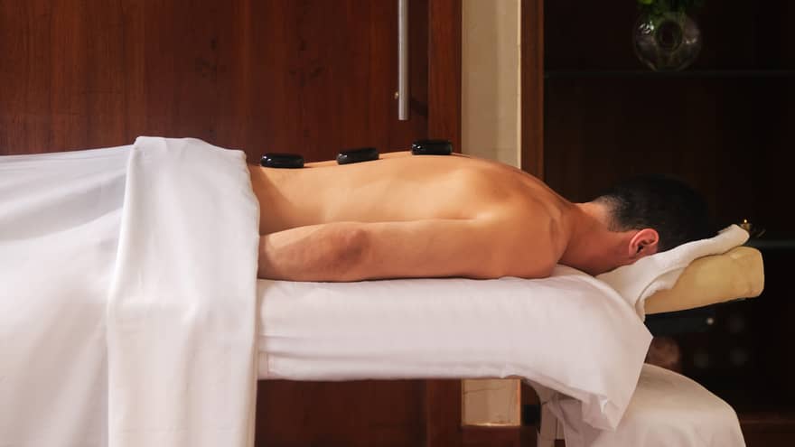 A guest laying on a spa table with hot stones on their back