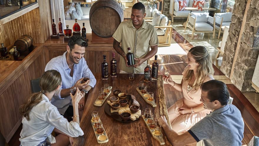 Group of laughing friends sit around table at a rum class