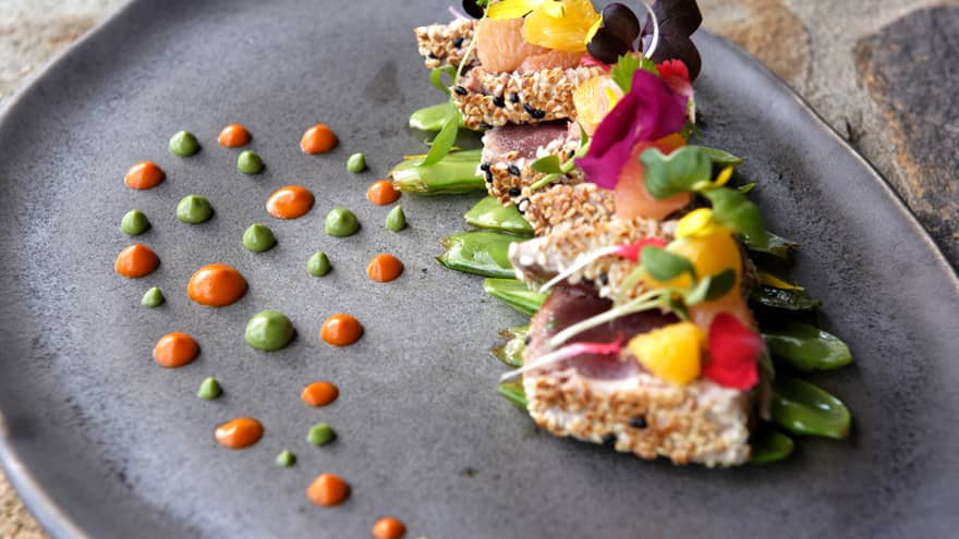 Sesame-crusted tuna topped with colourful edible flowers and green & orange dots