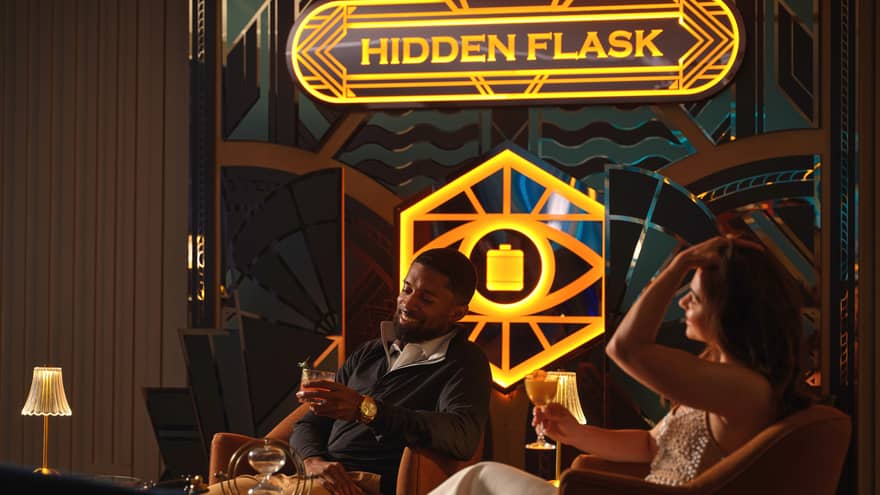 Two guests sitting in chairs beside a window and holding drinks