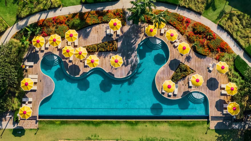 A pool surrounded by plants and yellow umbrellas.