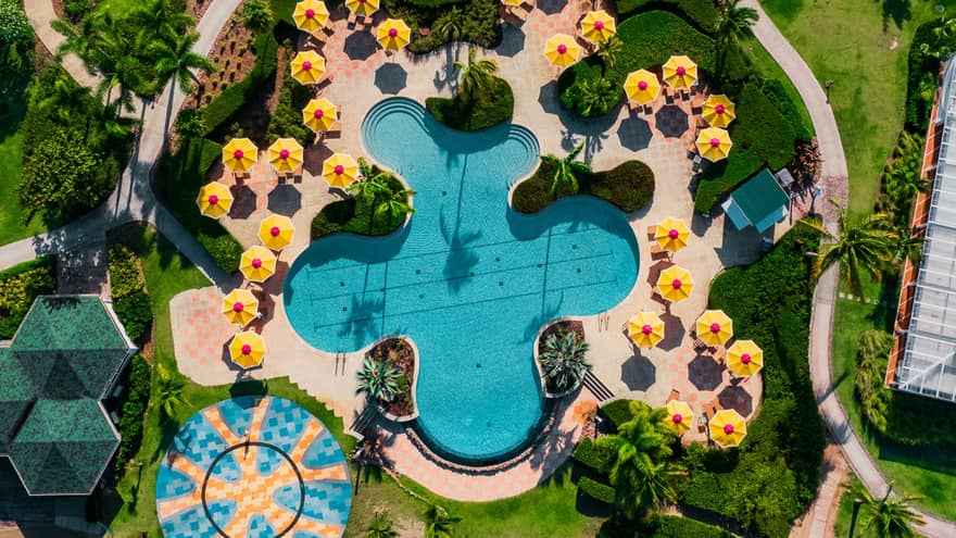 A birds eye view of a pool with yellow umbrellas around it.