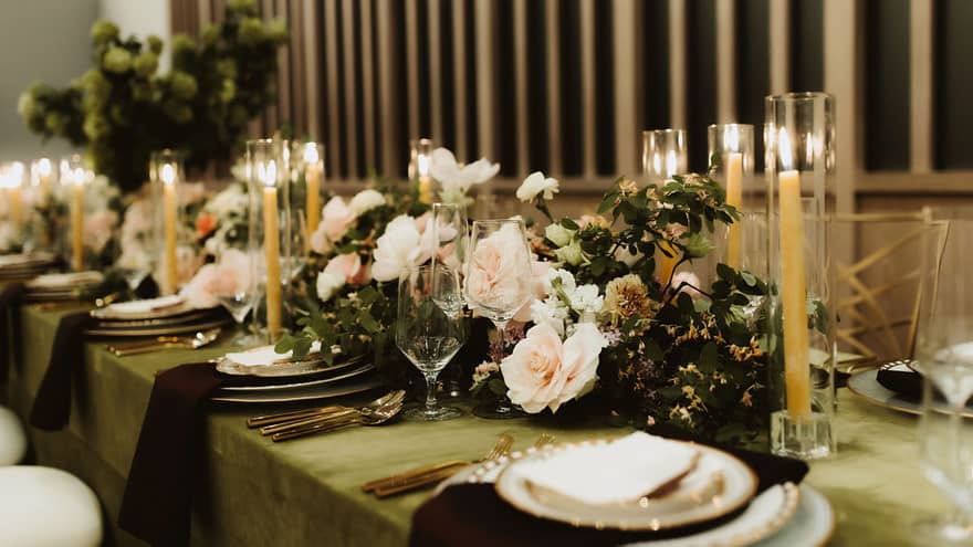 A long table with candles, flowers, plates and utensils.