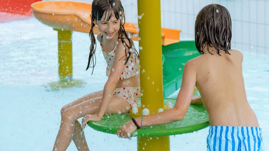 Two children playing on colourful feature of an indoor pool