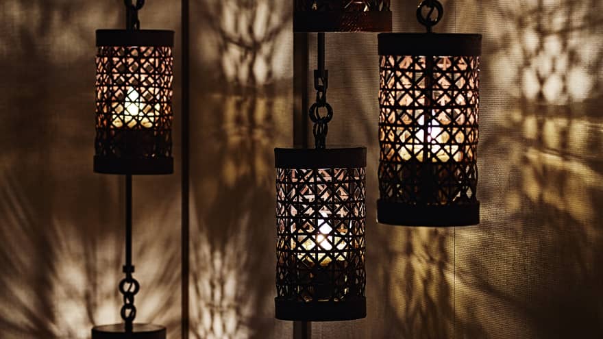 Close-up of black lanterns hanging from chains, light reflected on walls