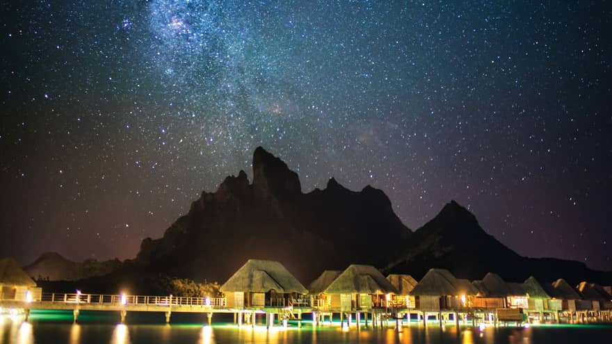 Illuminated Four Seasons Resort Bora Bora beneath a blanket of stars at night