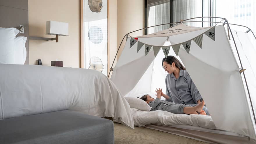 Parent and child in pyjamas playing together inside a cozy tent with bunting decorations