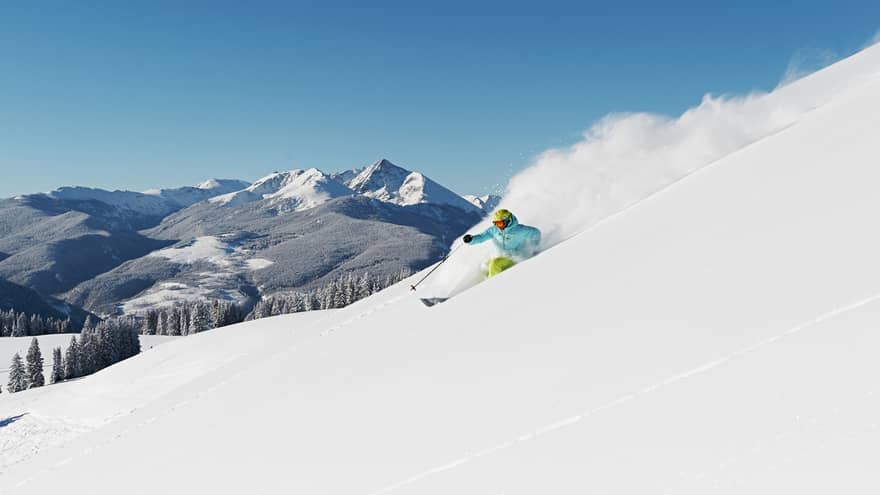 Person skiing down snow covered mountain top