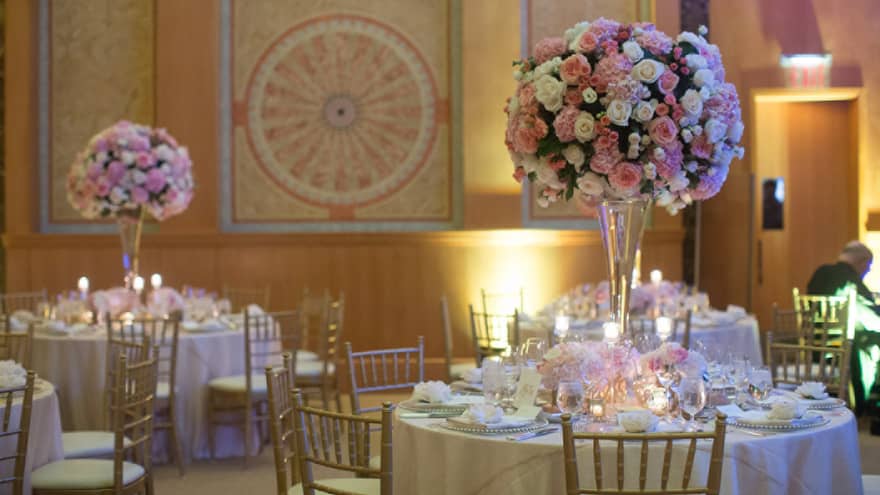 Wedding banquet, round tables with large pink and white floral arrangements in tall glass vases