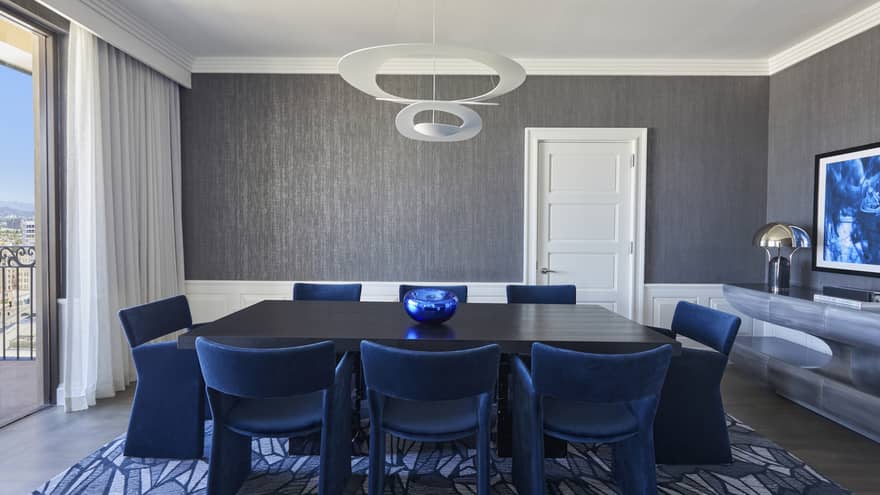 Dining room with black table and royal blue chairs, grey walls, blue carpet and floor-length window