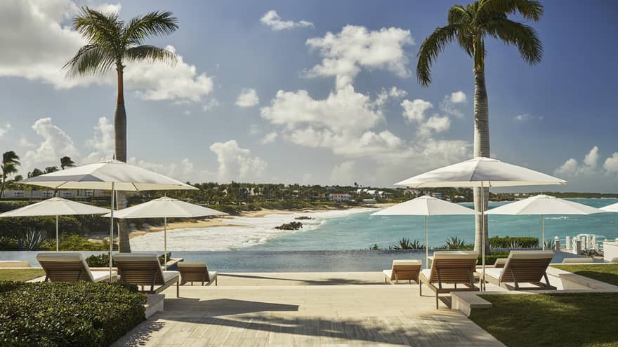 White umbrellas, lounge chairs on sunny patio overlooking ocean and beach