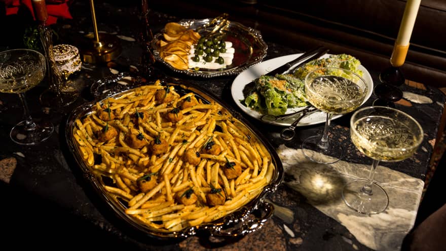 Several dishes of food, including a platter of French fries, a plate of salad and a glass of Champagne,Several dishes of food, including a platter of French fries, a plate of salad and a glass of Champagne