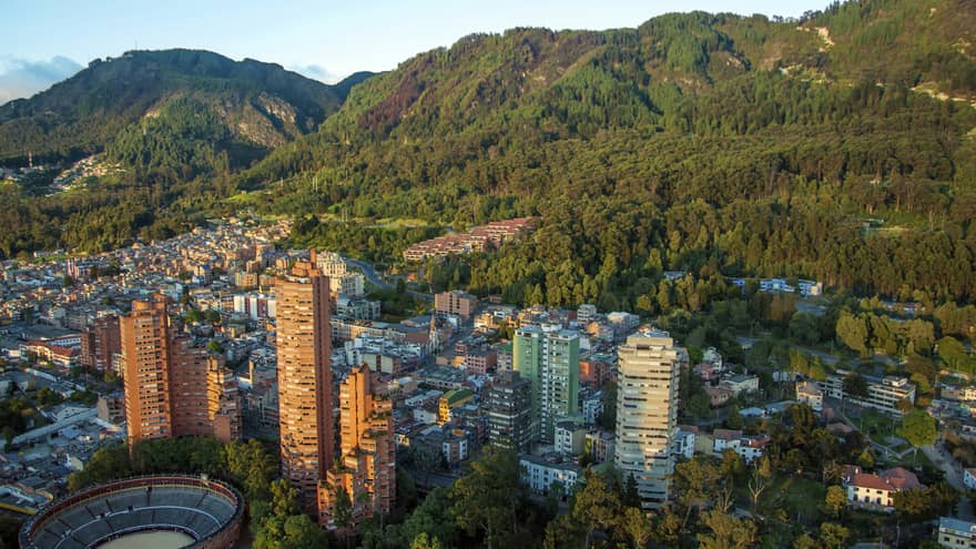 Aerial view of Bogota city high rises, houses and dome sports field on sunny day