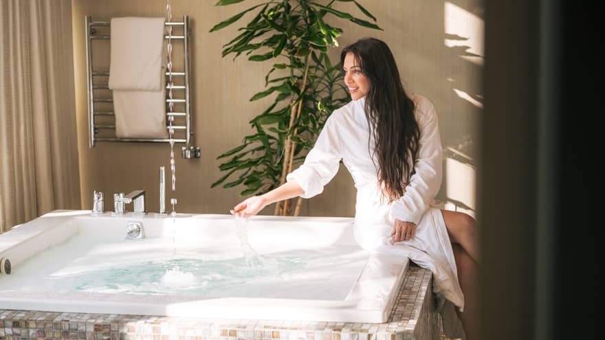 Woman sits at side of spa hot tub with spa robe on
