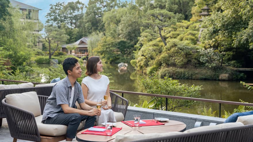Couple relaxes with glasses of champagne on a riverside terrace