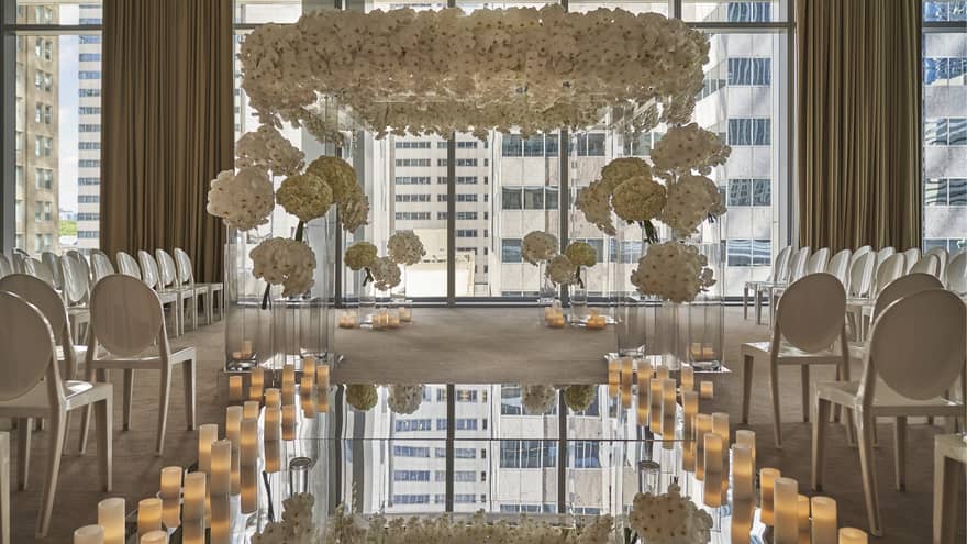 Wedding ceremony set up in event room, mirror aisle lined with candles leading to flower covered altar
