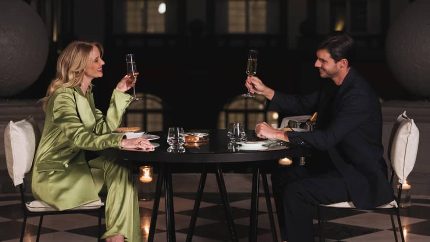 A man and woman drinking in a dimly lit room at a dark table.