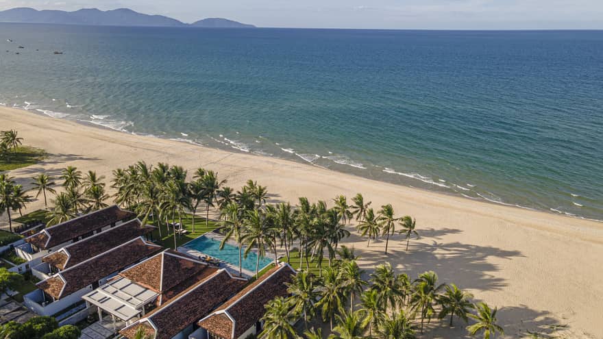 5 Bedroom Beachfront Pool Villa aerial shot with ocean and mountain views, palm trees and blue skies