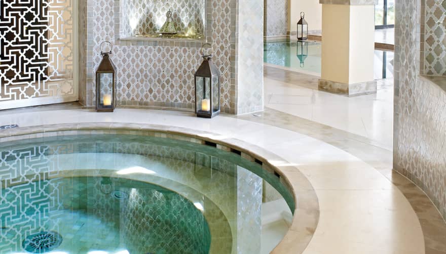 Small round whirlpool tub surrounded by decorative white detail wall, lanterns