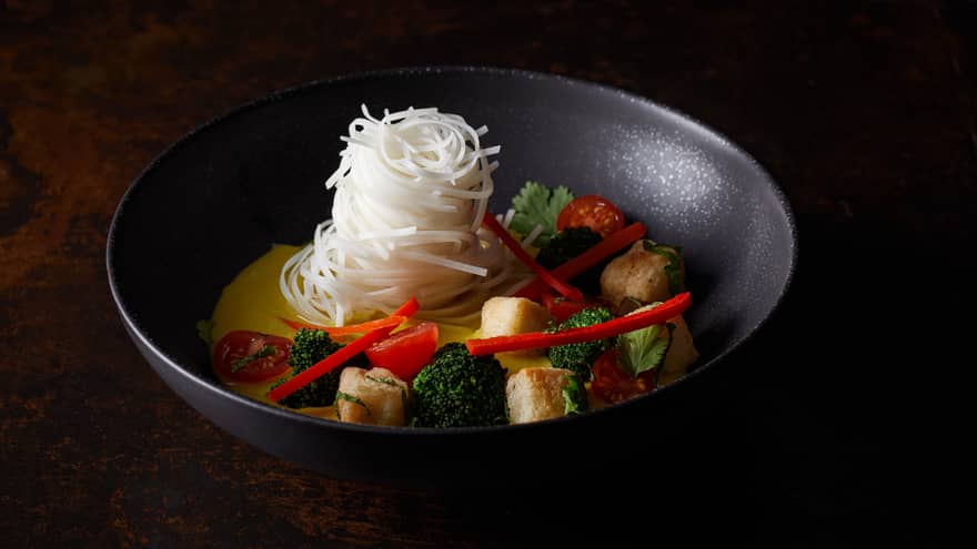 Tofu Laksa prepared with rice noodles, broccoli, tomatoes and peppers