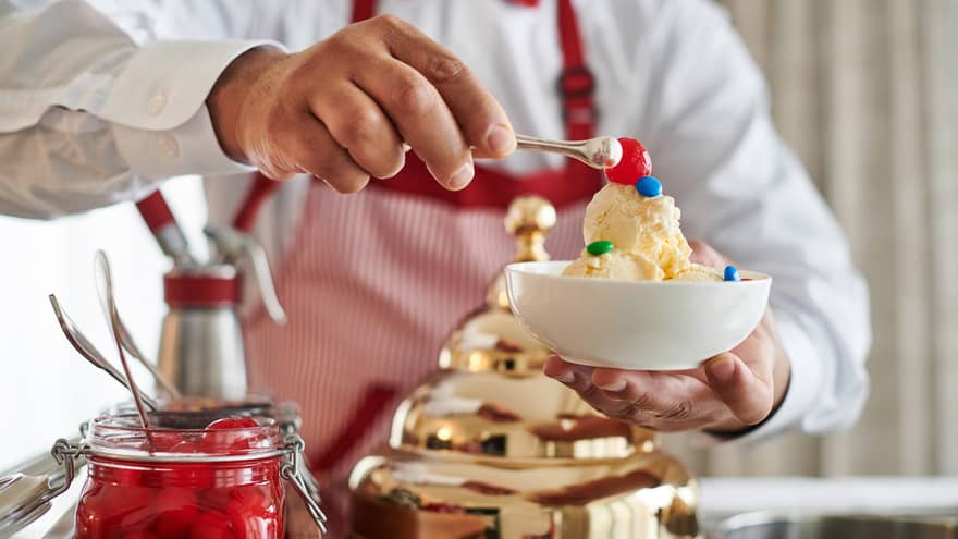 Man making an ice cream sundae from a retro Ice Cream Cart
