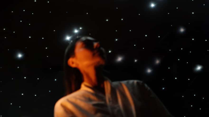 Guest wearing white spa robe stands in front of a ceiling lit to resemble a night sky filled with stars