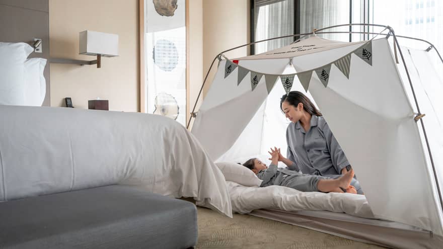 Parent and child in pyjamas playing together inside a cozy tent with bunting decorations