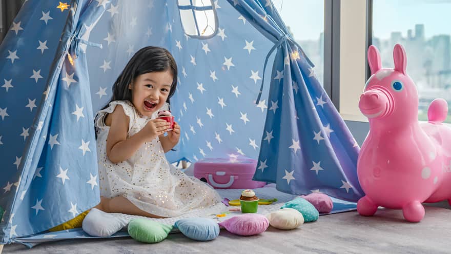 Smiling child playing with toys in a star-patterned tent