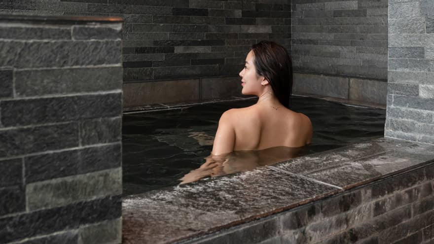 Female guest soaks in the grey stone onsen bath