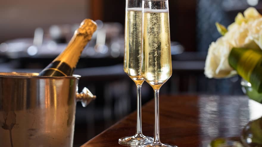 Close-up of two glasses of bubbly Champagne, bottle in ice bucket